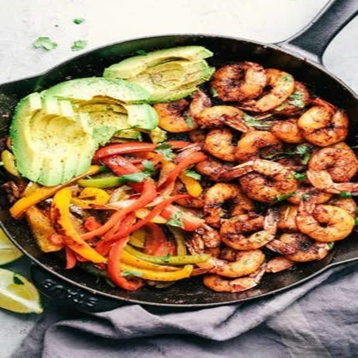 The ingredients for 20-Minute Skillet Shrimp Fajitas with avocado slices in a pan