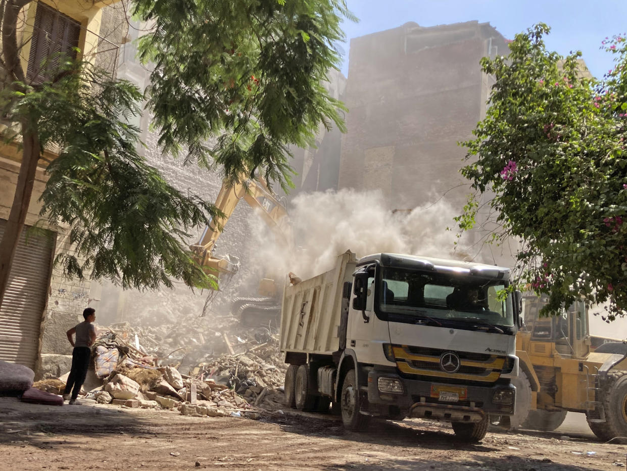 Residents and rescue workers sift through the rubble of a collapsed building in El-Weili neighborhood, Cairo, Egypt, Friday, June 17, 2022. A five-story apartment building collapsed in the Egyptian capital early Friday, killing numerous people according to officials. (AP Photo/Ahmed Hatem)