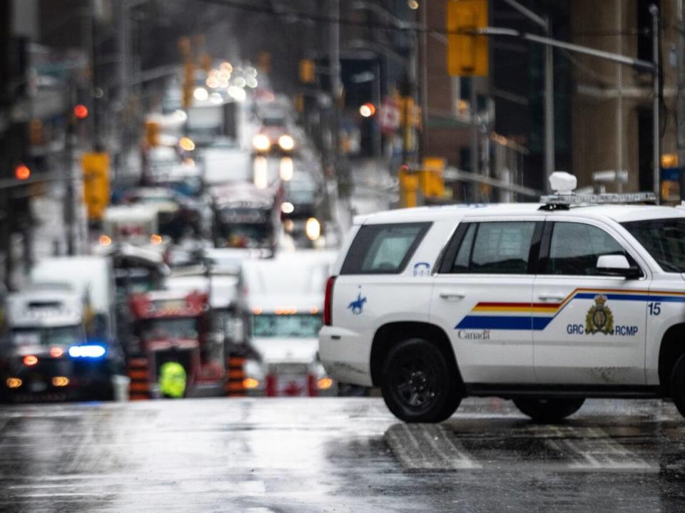 An RCMP vehicle passes in front of a blockade of trucks downtown Ottawa on Feb. 17, 2022. (Robert Bumsted/Associated Press - image credit)