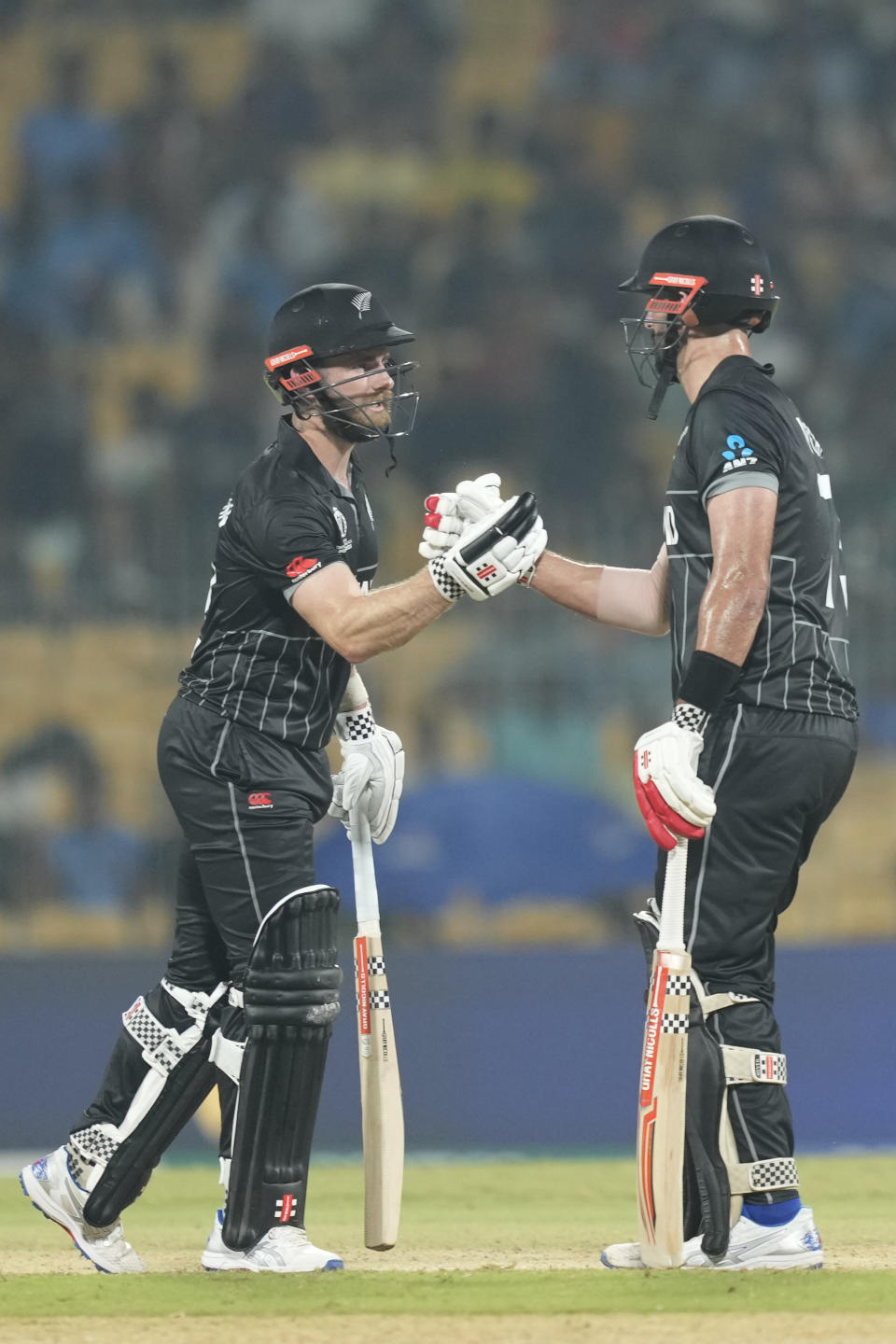 New Zealand's Daryl Mitchell, right, celebrates his fifty runs with New Zealand's captain Kane Williamson during the ICC Men's Cricket World Cup match between New Zealand and Bangladesh in Chennai , India, Friday, Oct. 13, 2023. (AP Photo/Eranga Jayawardena)