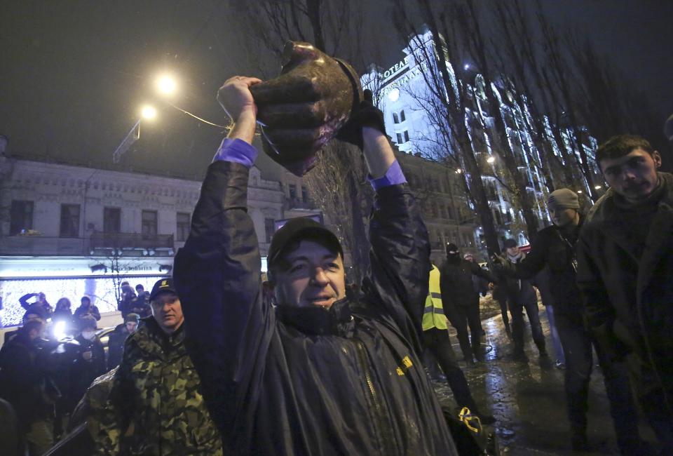 A man holds a part of a statue of Soviet state founder Vladimir Lenin which was toppled by protesters during a rally organized by supporters of EU integration in Kiev