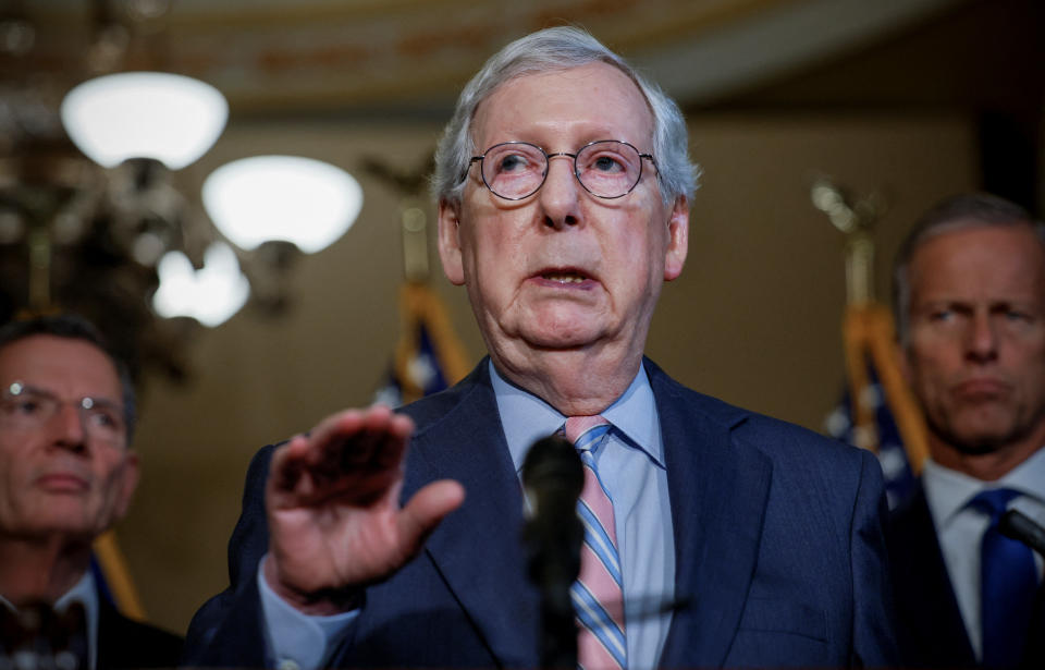 Senate Minority Leader Mitch McConnell stands at a microphone as he answers reporters’ questions.