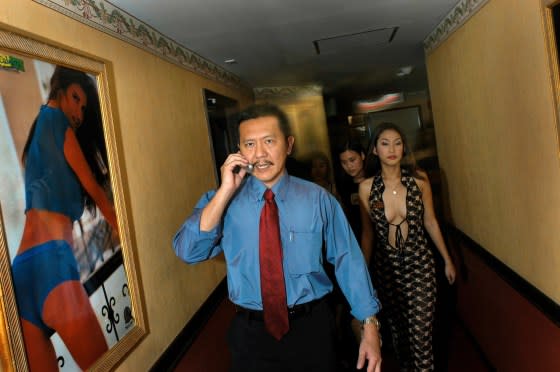 Chuwit Kamolvisit, then 42, talks on his mobile phone as he walks down the corridor of the Copacabana, one of his Bangkok establishments, on Oct. 2, 2003. <span class="copyright">Gerhard Joren—LightRocket/Getty Images</span>