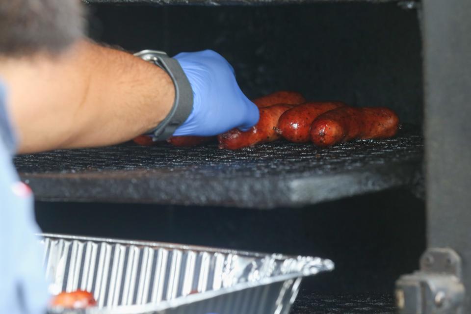 Co-owner Andrew Peña pulls out sausage links at Full Send Barbecue in downtown Corpus Christi Friday, March 15, 2024.