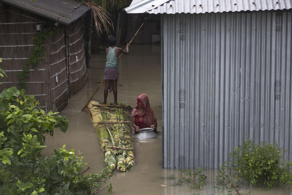 An Indian flood affected woman carries drinking water as a boy rows a makeshift banana raft in Pabhokathi village along the river Brahmaputra, east of Gauhati, Assam, India, Monday, July 15, 2019. After causing flooding and landslides in Nepal, three rivers are overflowing in northeastern India and submerging parts of the region, affecting the lives of more than 2 million, officials said Monday. (AP Photo/Anupam Nath)