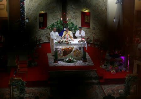 Iraqi Christians pray during a mass on Christmas at St George Chaldean Catholic Church in Baghdad, Iraq December 25, 2018. Picture shot through a wooden fence. REUTERS/Thaier Al-Sudani