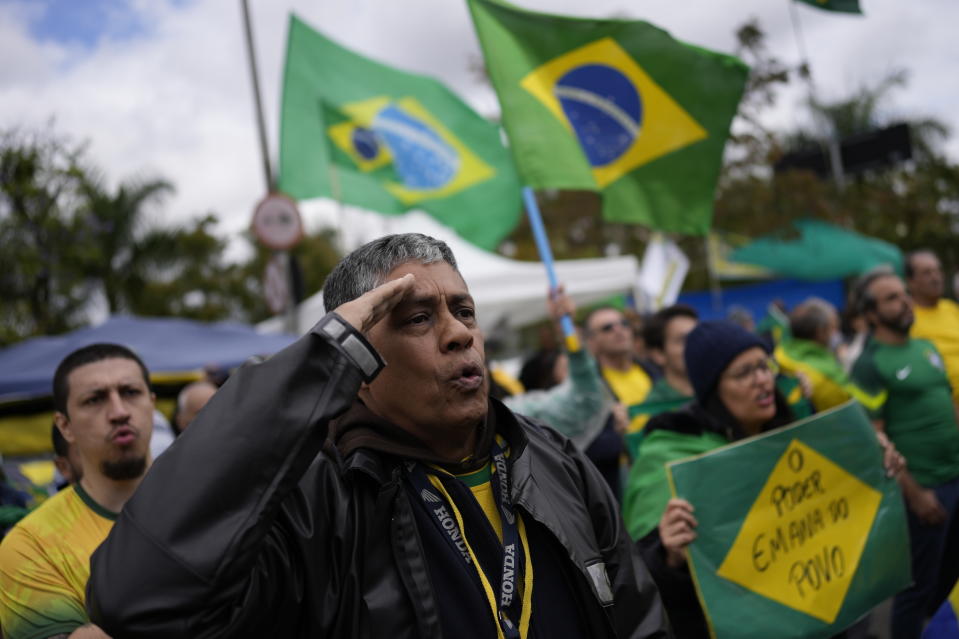 FILE - A supporter of Brazilian President Jair Bolsonaro salutes while singing the nation's anthem outside a military base during a protest against his reelection defeat in Sao Paulo, Brazil, Nov. 3, 2022. Supporters of incumbent President Jair Bolsonaro who refuse to accept his narrow defeat in October’s election have blocked roads and camped outside military buildings while pleading for intervention from the armed forces or marching orders from their commander in chief. (AP Photo/Matias Delacroix, File)