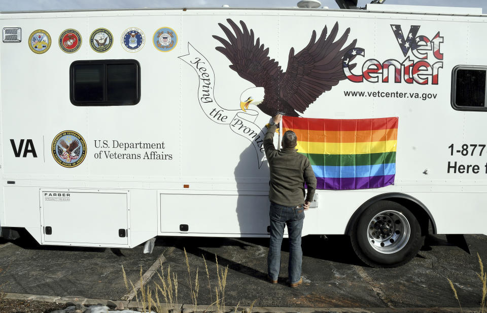 Austin Wilmarth, outreach coordinator for the Colorado Springs Vet Center, attaches a gay pride flag to a mobile counseling center near Club Q in Colorado Springs, Colo., on Wednesday, Nov. 23, 2022. The center, which is run by the U.S. Department of Veterans Affairs, offered counseling and outreach services to veterans, service members and the community following a shooting at the gay night club that killed five people Saturday night. (AP Photo/Thomas Peipert)