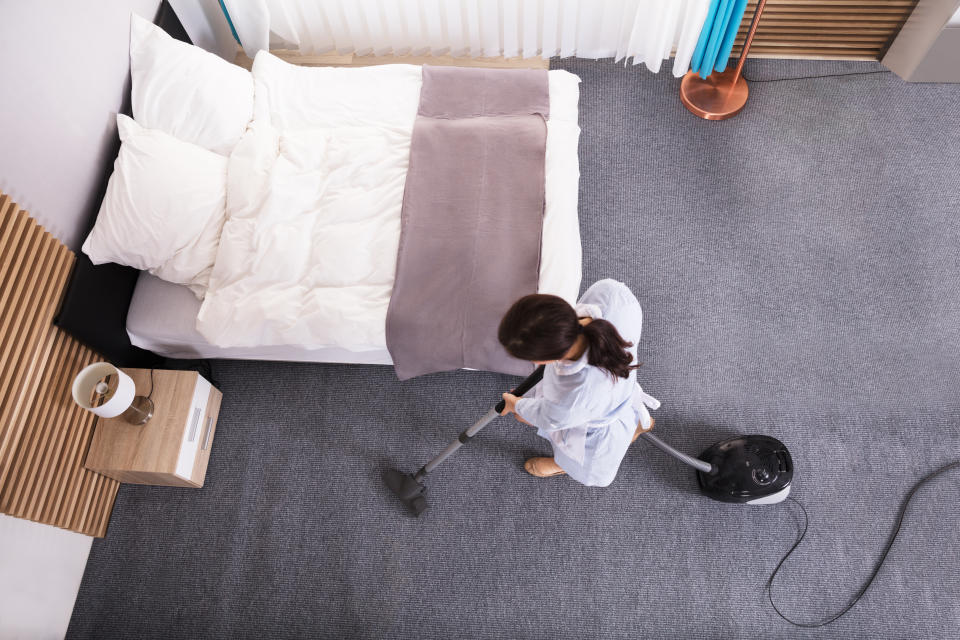 Happy Young Housekeeper Cleaning Carpet With Vacuum Cleaner In Hotel Room