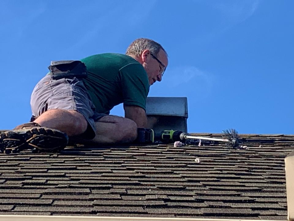 Ryan Arledge gets on a roof to clean built-up lint from a dryer vent July 7, 2023.
