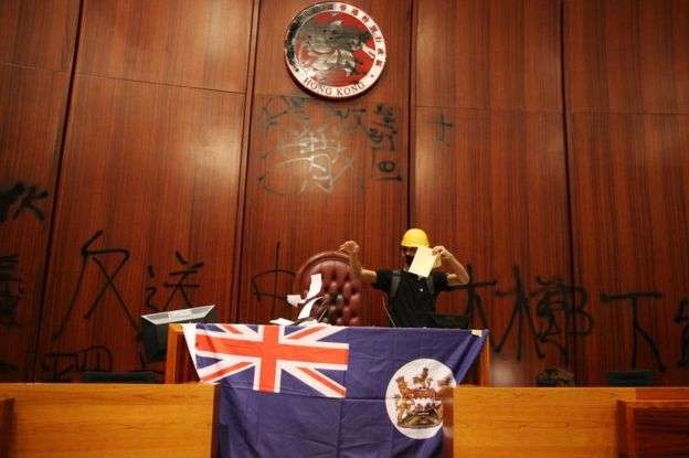 示威者在香港立法會會議廳塗污區徽，展示港英旗幟。（BBC中文網）
