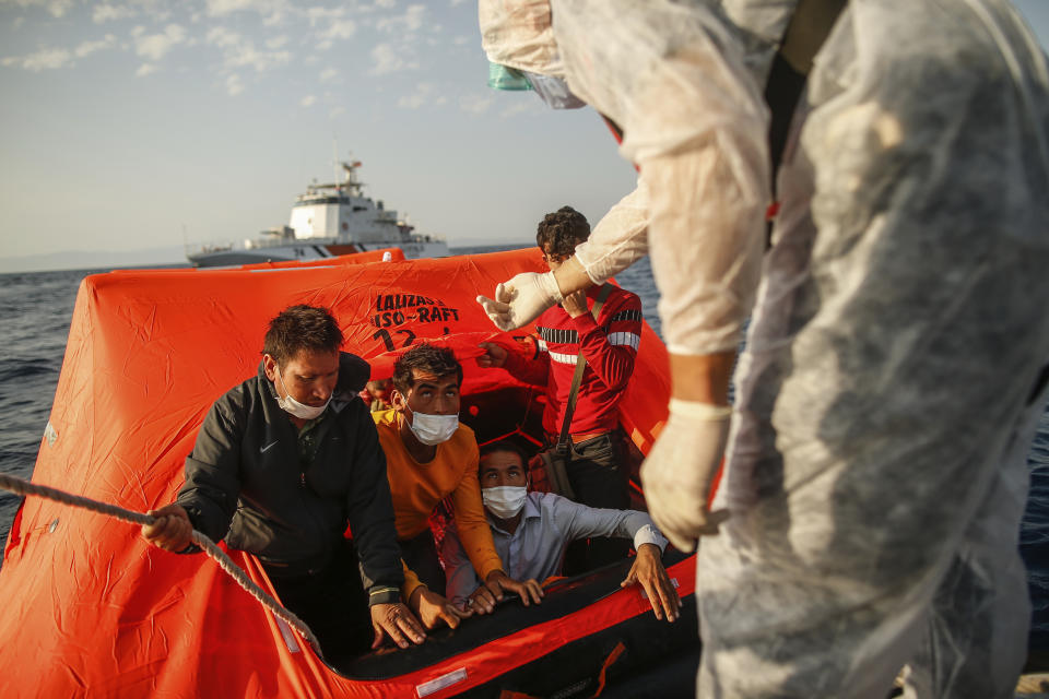 Turkish coast guards officers on their vessel, wearing protective gear to help prevent the spread of coronavirus, talk to migrants on a life raft during a rescue operation in the Aegean Sea, between Turkey and Greece, Saturday, Sept. 12, 2020. Turkey is accusing Greece of large-scale pushbacks at sea — summary deportations without access to asylum procedures, in violation of international law. The Turkish coast guard says it rescued over 300 migrants "pushed back by Greek elements to Turkish waters" this month alone. Greece denies the allegations and accuses Ankara of weaponizing migrants. (AP Photo/Emrah Gurel)