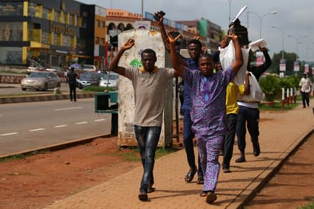 People raise their arms after the police dispersed members of the IMN from a street in Abuja