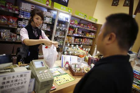 A visitor (R) collects prizes at a counter at Dynam's pachinko parlour in Honjo, north of Tokyo August 4, 2014. REUTERS/Issei Kato