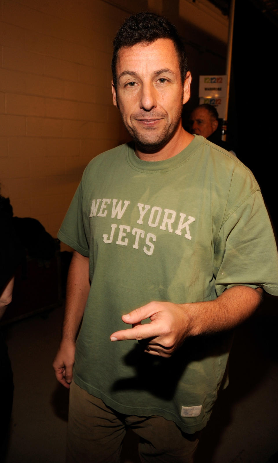 Man in casual attire with a 'New York Jets' t-shirt, gesturing with his hand