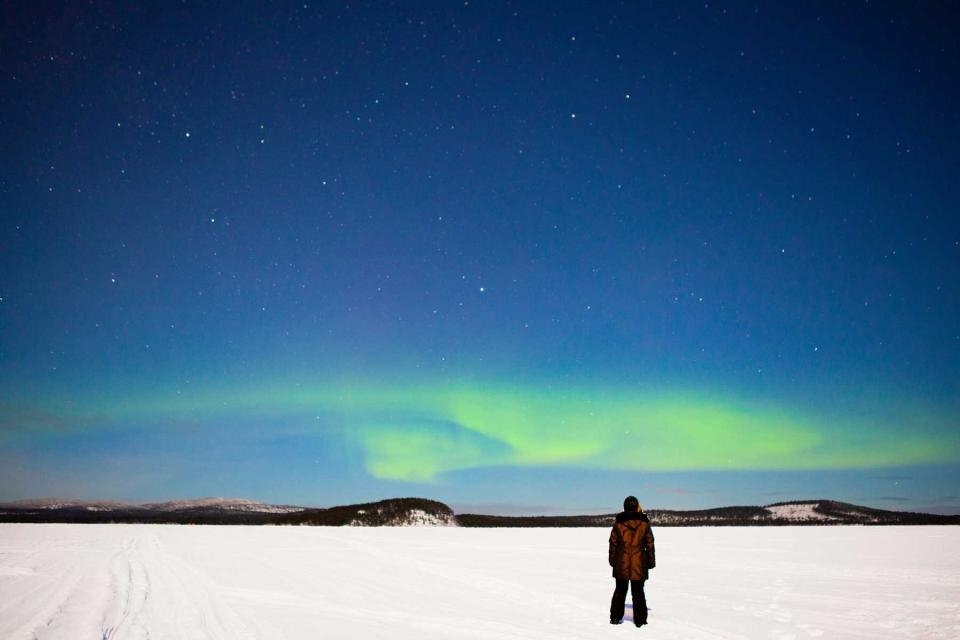 Person seeing northern lights during winter in Inari, Finland