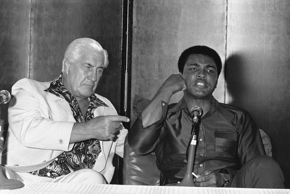 World heavyweight boxing champion Muhammad Ali, together with ex-pro wrestler Freddie Blassie, meets the press at a Tokyo Hotel on June 19, 1976 in Japan. (AP Photo/KCK)