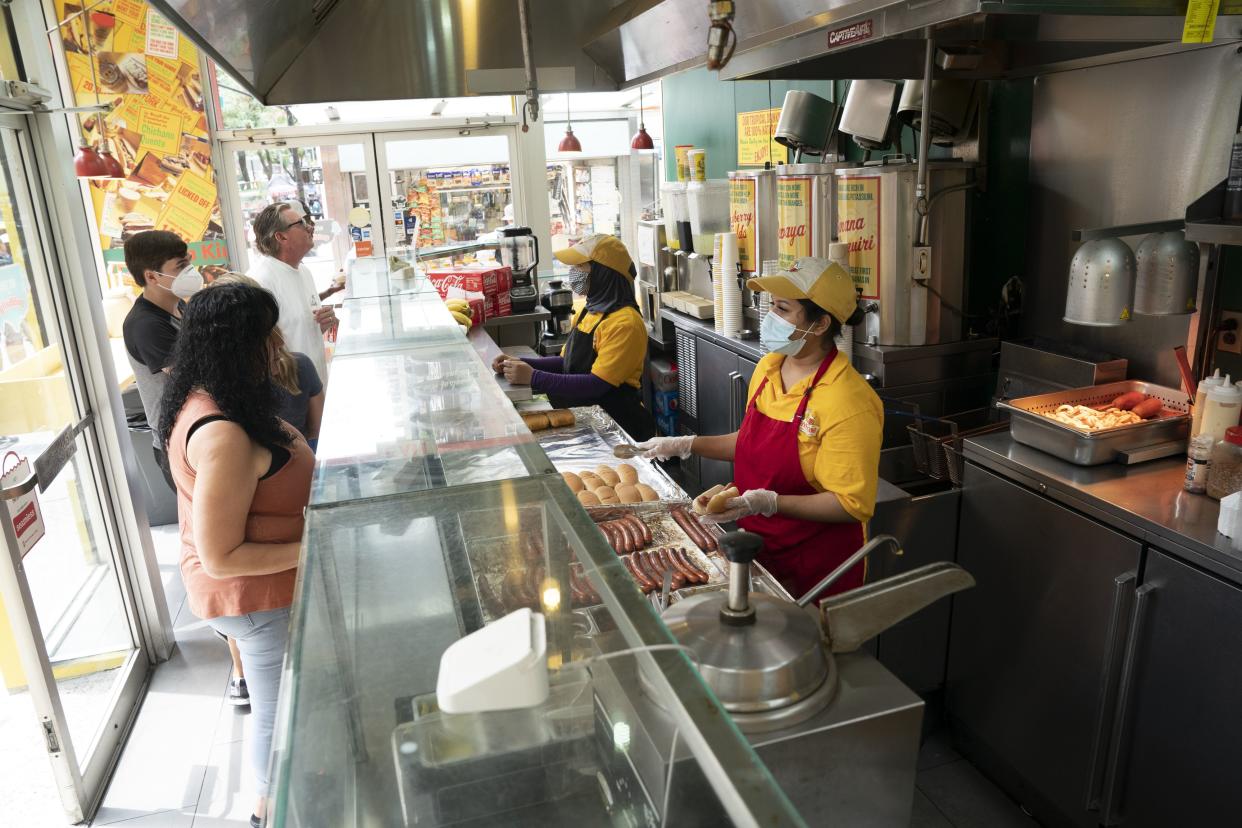 Employees of Papaya King, an Upper East Side staple, serve customers Friday, July 8, 2022 in Manhattan, New York. 