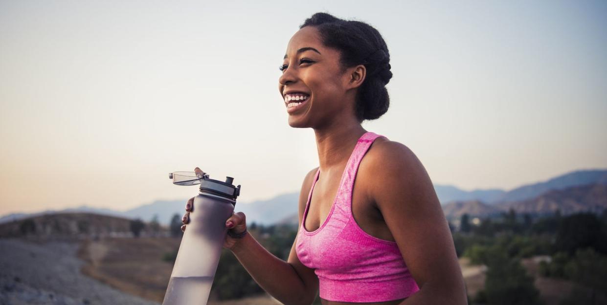 a woman holding a water bottle and smiling