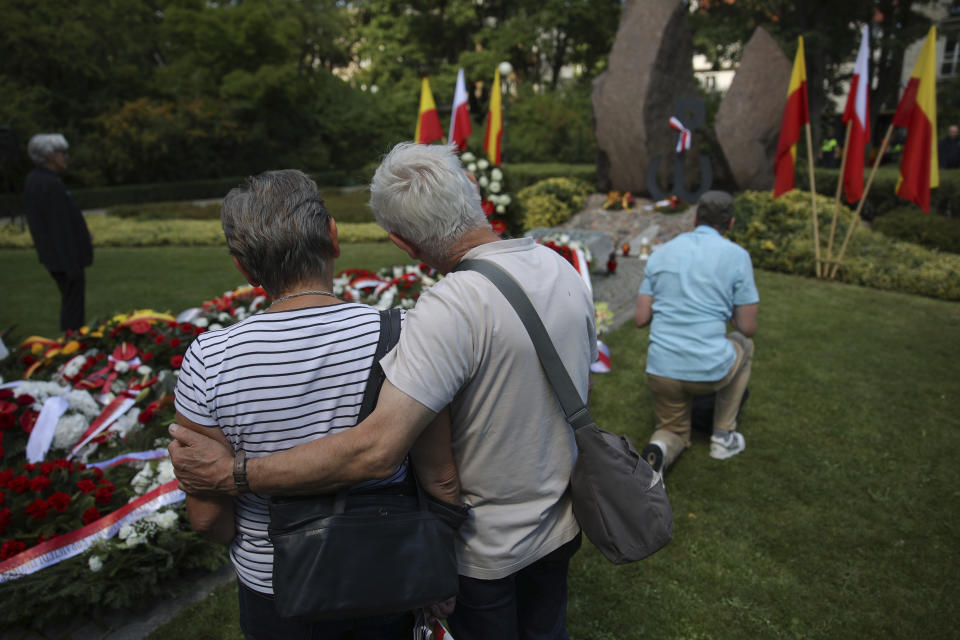 People stand in front of the monument commemorating the fighters and victims of the 1944 Warsaw Uprising, in Warsaw, Poland, Monday Aug. 1, 2022. Poles are marking the 78th anniversary of the Warsaw Uprising, a doomed revolt against Nazi German forces during World War II. (AP Photo/Michal Dyjuk)