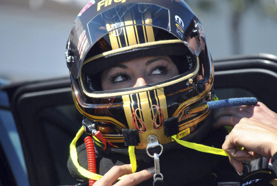 FILE - Drag racer Leah Pritchett, now Leah Pruett, tightens her helmet before making a pass at the NHRA Gatornationals at Gainesville Raceway, in Gainesville, Fla., in this Saturday, March 17, 2018, file photo. Tony Stewart, who fell in love with NHRA while tagging along with fiancée Leah Pruett at her races the past two seasons, will be an official part of the sport in 2022. The NASCAR Hall of Fame driver will add two fulltime NHRA entries to Tony Stewart Racing next season — a Top Fuel entry for Pruett and a Funny Car for Matt Hagan. “It's a very unique opportunity to control my own destiny with my almost-husband in a sport I'm absolutely passionate about,” Pruett told The Associated Press. (AP Photo/Mark Long, File)