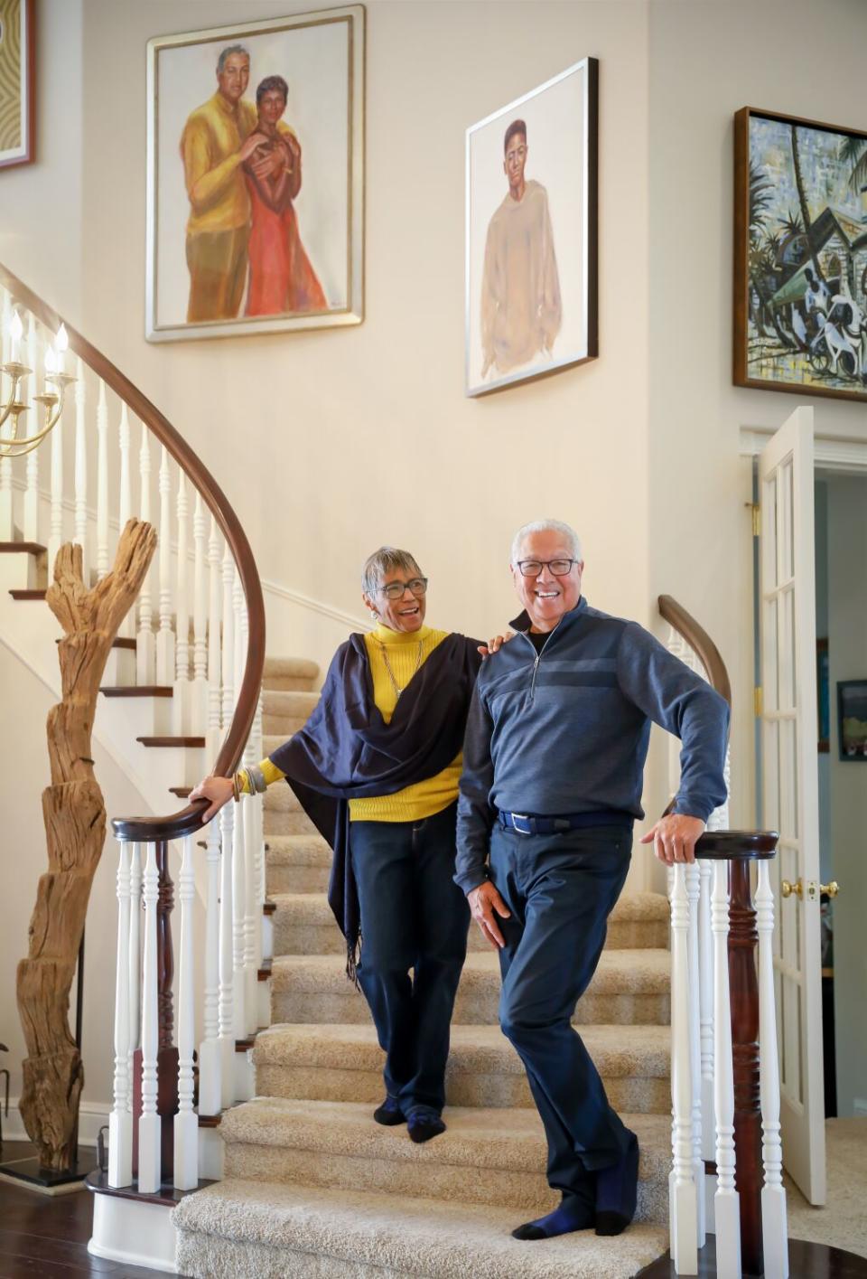 A woman and man stand on a home's curving staircase.