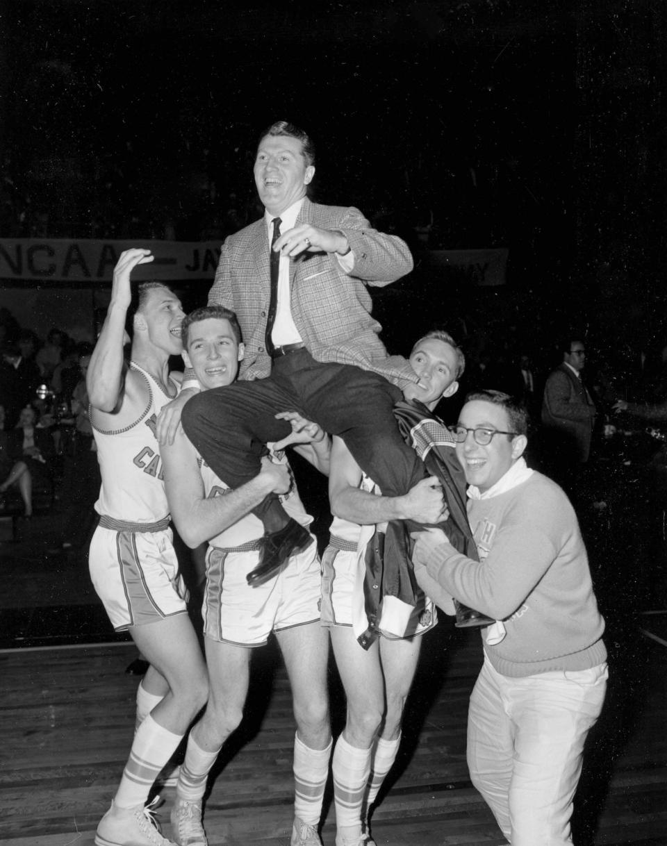 FILE - North Carolina players hoist head coach Frank McGuire as they celebrate their 54-53 victory over Kansas in the NCAA college basketball championship final in Kansas City, Mo., March 23, 1957. (AP Photo/William P. Straeter, File)