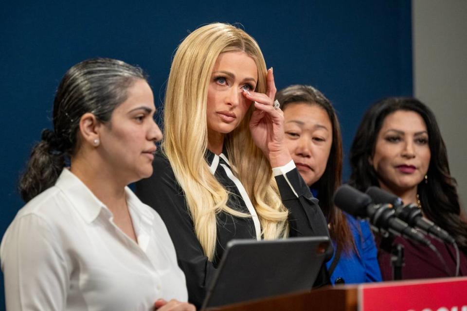 Celebrity advocate Paris Hilton wipes a tear as state Sen. Aisha Wahab, D-Hayward, talks during a bipartisan press conference to highlight Senate Bill 1043, which is intended to bring transparency and accountability to youth residential facilities, on Monday. Hilton was sent to one such facility when she was 17. Also at the podium are Sens. Janet Nguyen, R-Huntington Beach, right, and Susan Rubio, D-Los Angeles County, far right.