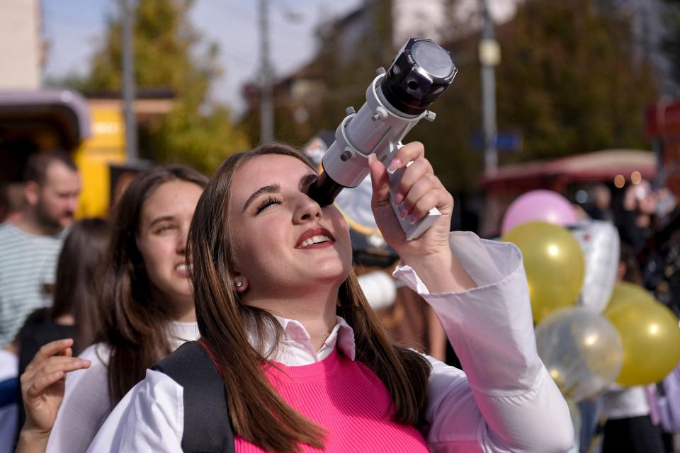 A woman uses a telescope to watch a partial solar eclipse in Pristina on Oct. 25, 2022.