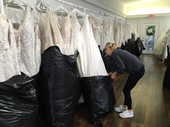 Baylie Berry, assistant manager of The White Magnolia Bridal Collection in flood-prone San Marco used black plastic trash bags Wednesday, September 28, 2022, to protect the shop's sample wedding gowns from possible flood waters resulting from Hurricane Ian. Customer gowns were taken out of the store to higher ground. [Teresa Stepzinski/Florida Times-Union]