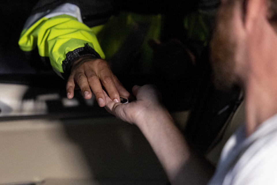 A Metropolitan Police Department officer hands a driver an Apple AirTag during an event where police tracking devices to drivers in an attempt to curb a rise in crime in Washington on Tuesday, Nov. 7, 2023. (AP Photo/Amanda Andrade-Rhoades)
