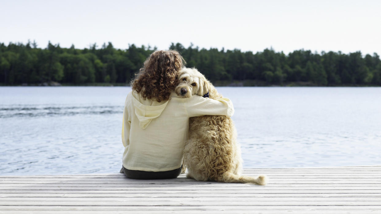  Women hugging dog on jetty: best things about owning a dog. 