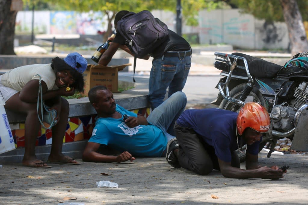 People take cover from gunfire during clashes between police and gangs in the Champs de Mars area next to the National Palace in Port-au-Prince, Haiti, Monday, April 8, 2024. (AP Photo/Odelyn Joseph)