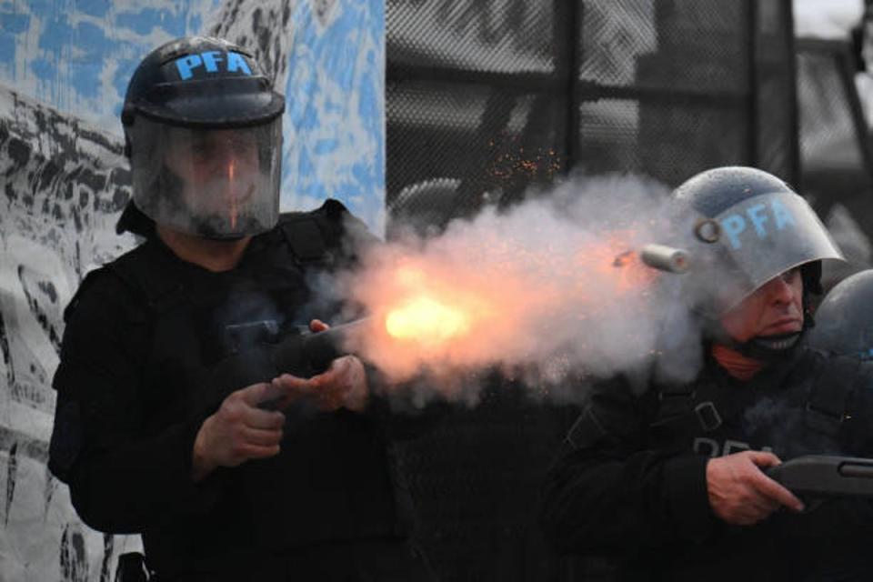 A riot police officer fires his gun during clashes with demonstrators near the National Congress in Buenos Aires on 12 June 2024 (AFP via Getty Images)