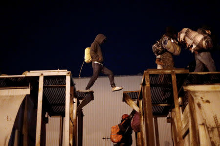 A Central American migrant, moving in a caravan through Mexico, crosses between the wagons of a freight train before embarking on a new leg of his travels, in Tlaquepaque, in Jalisco state, Mexico April 19, 2018. REUTERS/Edgard Garrido