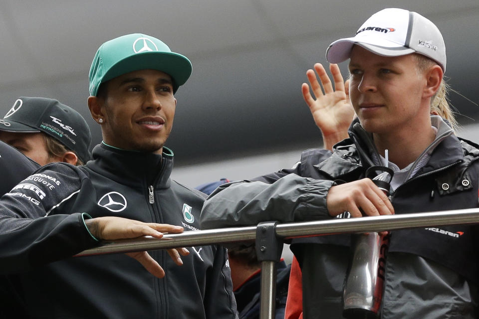 CORRECTS ID OF DRIVER AT RIGHT - Mercedes drivers Lewis Hamilton of Britain, left, and Kevin Magnussen of Denmark stand on a double decker during the driver's parade prior to the start of the Chinese Formula One Grand Prix at Shanghai International Circuit in Shanghai, China, Sunday, April 20, 2014. (AP Photo/Alexander F. Yuan)