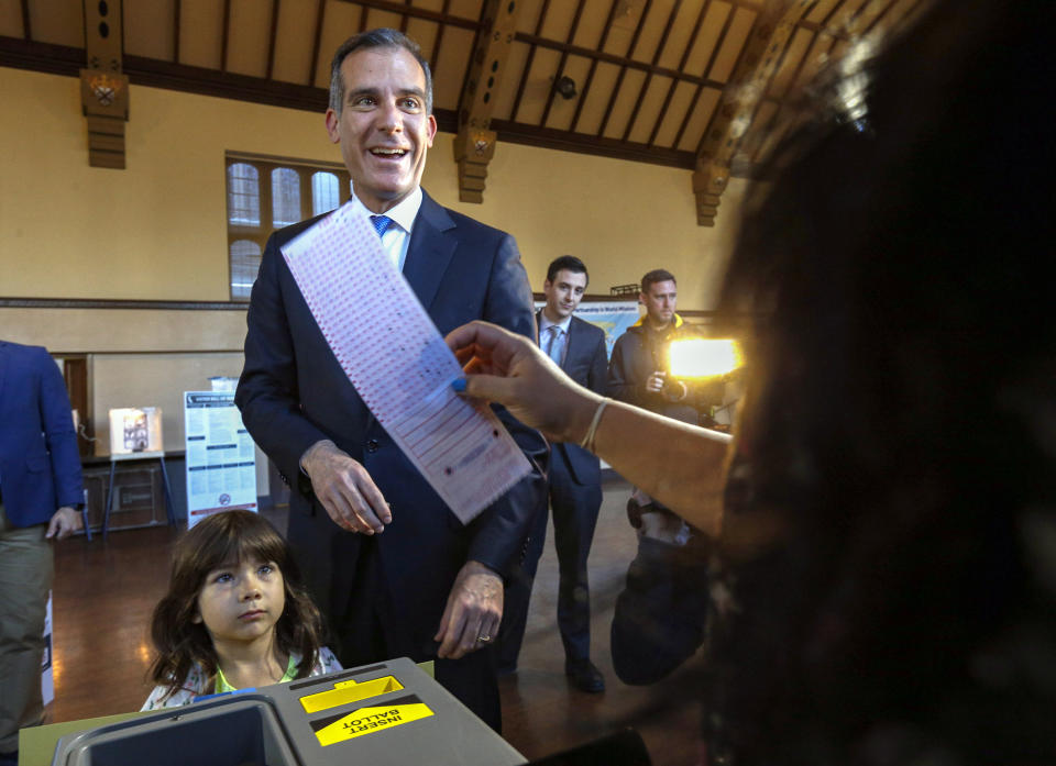 FILE - In this March 7, 2017, file photo, Los Angeles Mayor Eric Garcetti casts his election ballot with his daughter, Maya, in Los Angeles. Garcetti said Thursday, Dec. 17, 2020 that his now 9-year-old daughter, Maya, has tested positive for COVID-19, and that he and his wife are quarantining at home. Garcetti said his daughter Maya felt ill on Monday, developed a fever and tested positive for COVID-19. He said he and his wife, Amy, have tested negative. Garcetti also said that he told the incoming Biden Administration earlier this week that he would not leave Los Angeles. (AP Photo/Nick Ut, File)