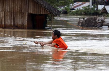 A man is pulled by rope as he returns to his house, which is partially submerged in heavy flooding brought by tropical depression "Agaton", in Butuan on the southern Philippine island of Mindanao January 21, 2014. REUTERS/Erik De Castro