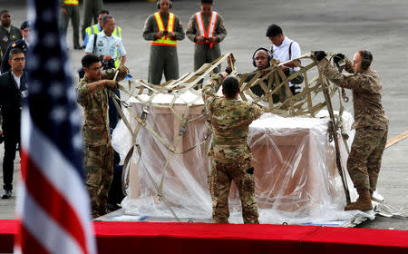 U.S Air Force personnel remove the cover of crates containing the bells of Balangiga, after their arrival at Villamor Air Base in Pasay, Metro Manila, Philippines December 11, 2018. REUTERS/Erik De Castro