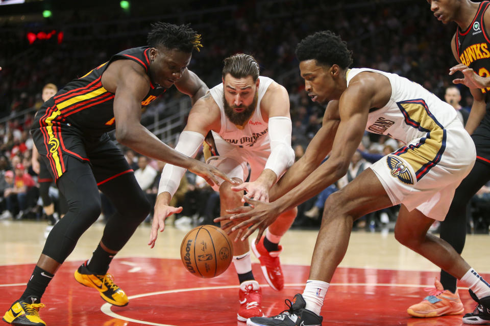 Atlanta Hawks center Clint Capela, left, reaches for the ball with New Orleans Pelicans center Jonas Valanciunas, center, and forward Herbert Jones, right, in the first half of an NBA basketball game Sunday, March 20, 2022, in Atlanta, Ga. (AP Photo/Brett Davis)