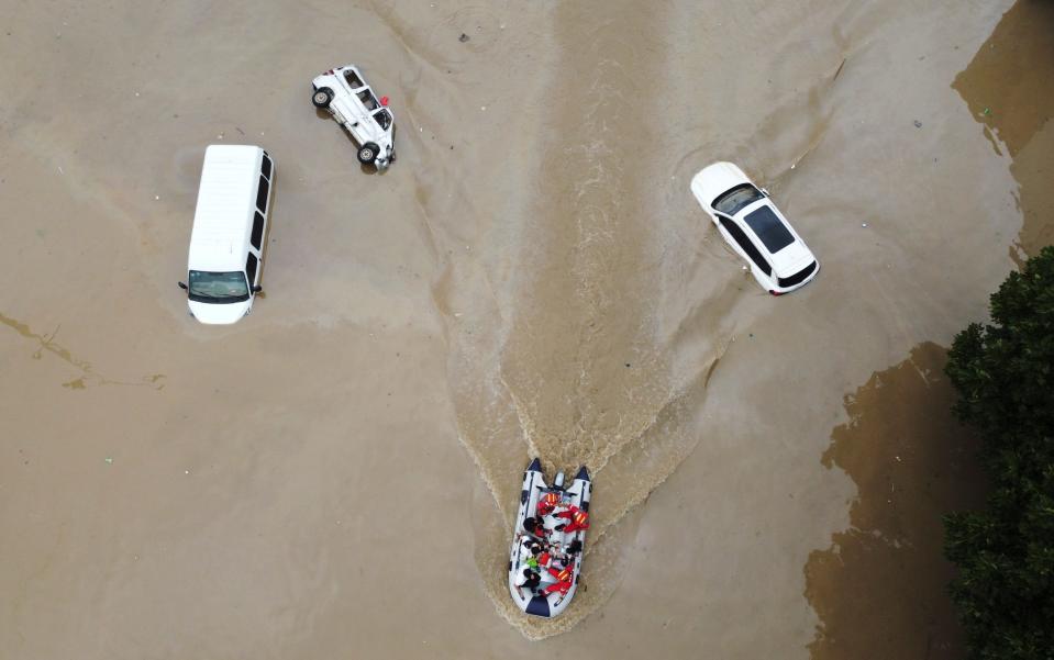 Rescue workers evacuate residents on a boat past stranded vehicles following heavy rainfall in Zhengzhou - REUTERS 