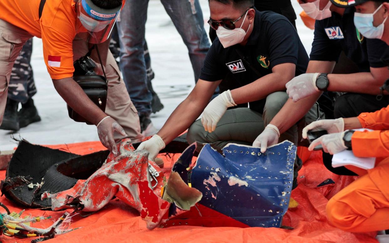 Investigators inspect debris found on the waters off Java Island around where a Sriwijaya Air passenger jet crashed - AP