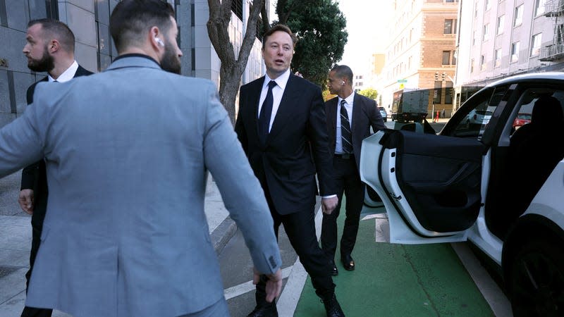 Elon Musk stands by his Tesla car after leaving the courthouse during an ongoing legal dispute surrounding his supposed 2018 plans to take Tesla private. It’s just one of many scandals surrounding the company that puts a damper on Tesla’s record profits.