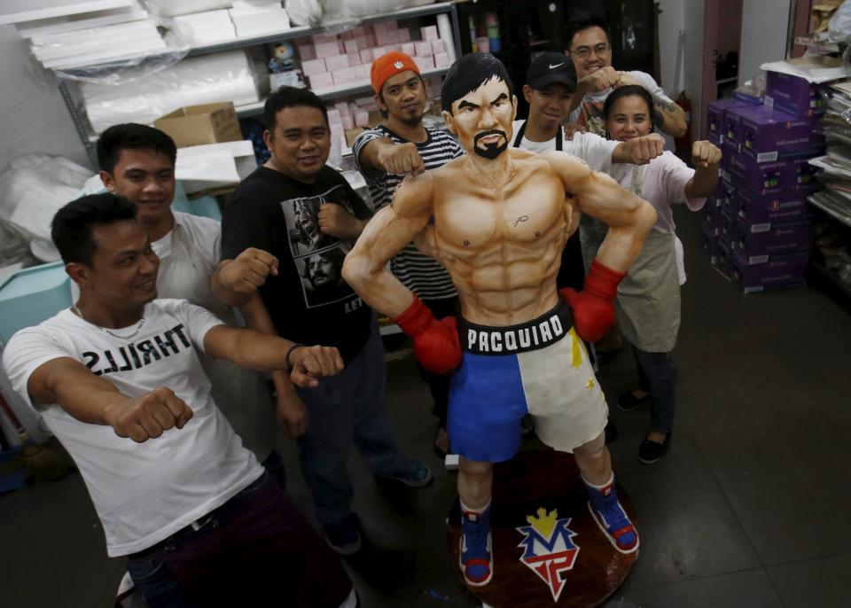 Workers from a bakery pose next to a life-size 70-kg chocolate cake of local boxing icon Manny Pacquiao for the media in Manila, Philippines May 2, 2015. From air-conditioned corporate boardrooms to steamy public gymnasiums, Filipinos are counting down the hours to Pacquiao's fight with undefeated American Floyd Mayweather Jr. in Las Vegas. The world welterweight championship bout, which is being called the "fight of the century," will bring the country to a standstill on Sunday and mark a rare period of unity for the poor Southeast Asian nation. The Pacquiao cake, which took two weeks to make, went on display on Saturday in Manila and slices will be given away after the bout. REUTERS/Erik De Castro