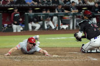 Cincinnati Reds' Spencer Steer, left, scores a run as Arizona Diamondbacks catcher Gabriel Moreno, right, makes a catch on a late throw during the eighth inning of a baseball game Monday, May 13, 2024, in Phoenix. (AP Photo/Ross D. Franklin)