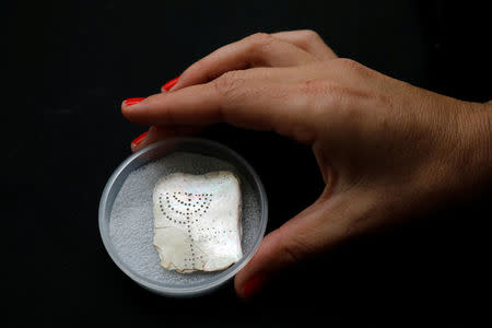 An archaeologist presents a menorah inscribed on a shell, which was found on the site of the old city of Caesarea, Israel April 26, 2017 REUTERS/Amir Cohen