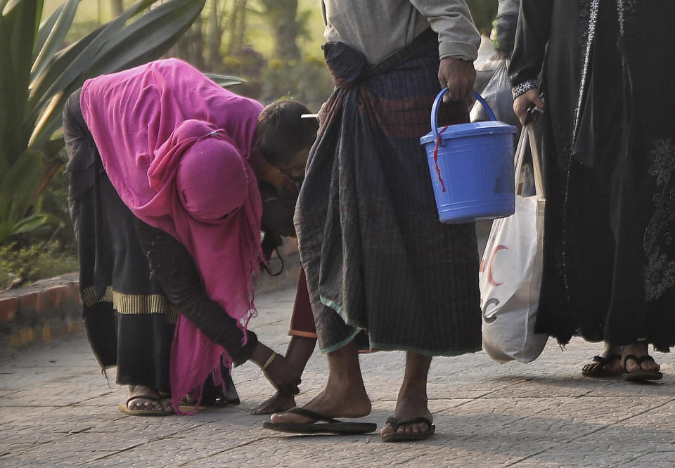 A Rohingya woman looks at a child's leg as they walk to board a naval vessel to be relocated to to the island of Bhasan Char, in Chattogram, Bangladesh, Saturday, Jan. 30, 2021. Authorities in Bangladesh sent a group of Rohingya refugees to a newly developed island in the Bay of Bengal on Saturday despite calls by human rights groups for a halt to the process. The government insists the relocation plan is meant to offer better living conditions while attempts to repatriate more than 1 million refugees to Myanmar would continue. (AP Photo/Azim Aunon)