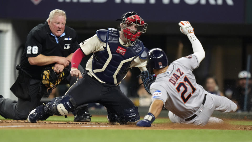 Houston Astros' Yainer Diaz (21) scores against Texas Rangers catcher Jonah Heim, center, as umpire Bill Miller (26) looks on during the sixth inning of a baseball game in Arlington, Texas, Friday, June 30, 2023. Diaz scored on a double by teammate Mauricio Dubon. (AP Photo/LM Otero)