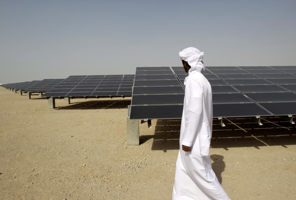 FILE - In this Jan. 16, 2011 file photo, an Emirati man pass by 10mw photovoltaic plant at Masdar City, a sustainable urban development powered by renewable energy in Abu Dhabi, United Arab Emirates. Although all six Gulf states remain heavily reliant on fossil fuels for state spending, each has taken steps to try and diversify their economies, with Saudi Arabia and the UAE leading aggressive efforts to attract other forms of investment in new industries. (AP Photo/Kamran Jebreili, File)