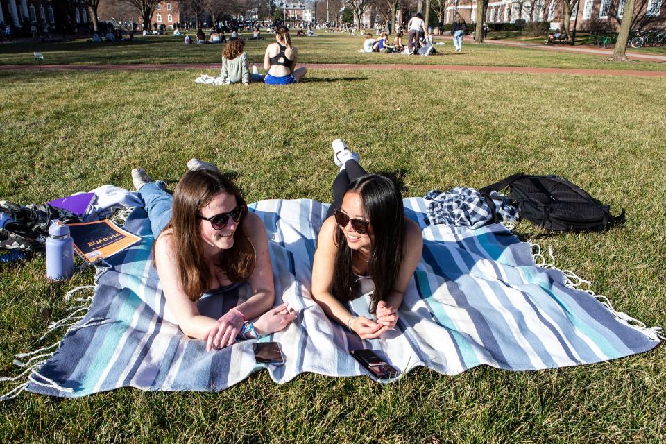 University of Delaware students, from left, Jennifer Werth, 21, and Caroline Anderson, 21, enjoy a sunny and warm winter day on The Green Campus Building in Newark, Thursday, Feb. 23, 2023.